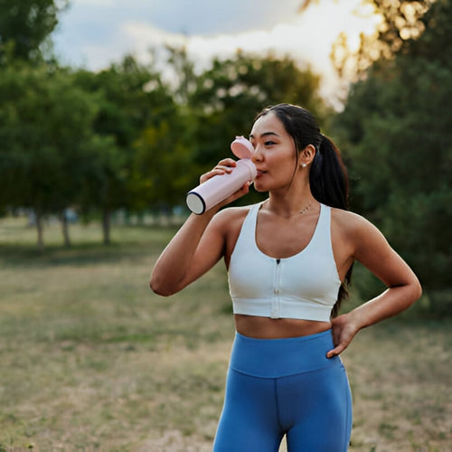 Latina woman outside in workout clothes drinking from water bottle