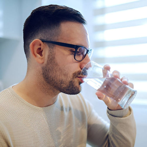 Man drinking water near window