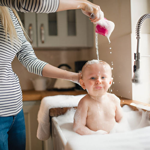 Baby taking bath in kitchen sink