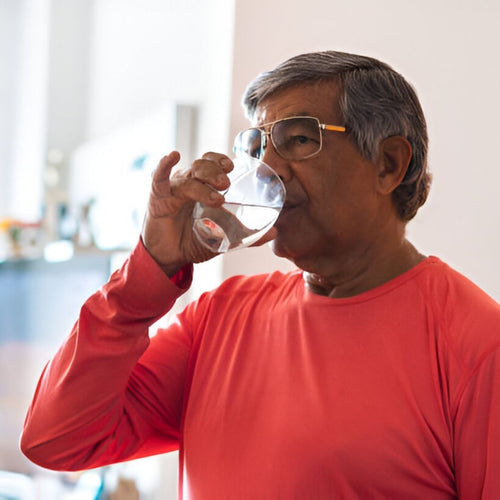 Older man with glasses drinking water